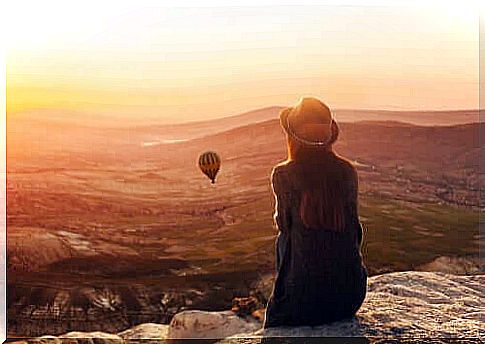 Woman observing landscape with flying balloon.